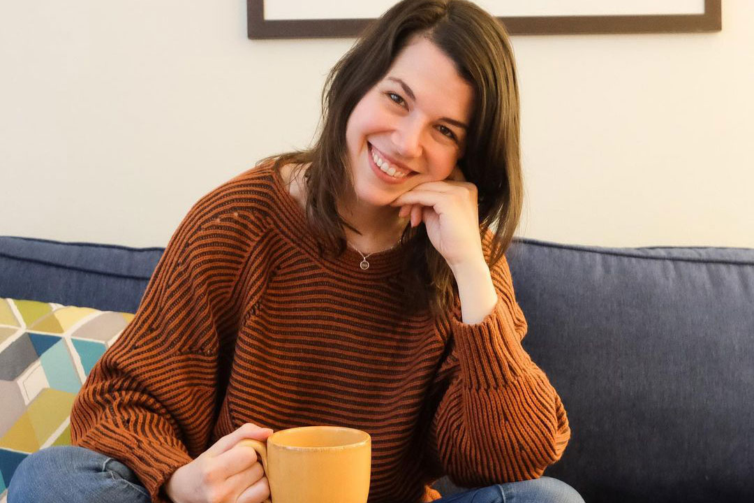 Laura sitting on a sofa holding a cup of coffee
