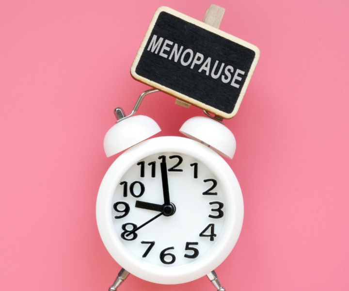 Image of a white alarm clock with a small sign that reads "menopause" attached to it